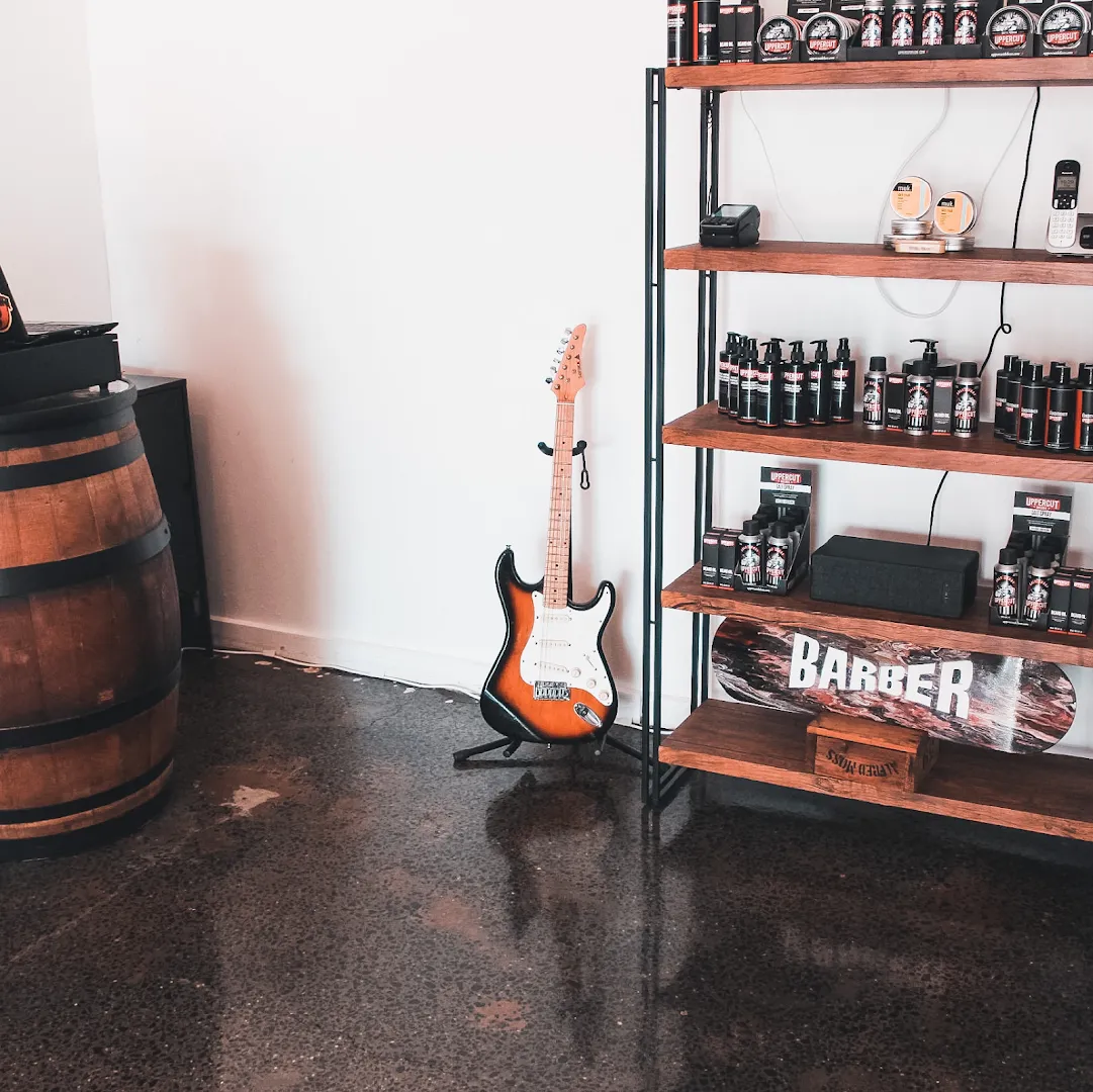 A Les Paul-style guitar and whiskey barrel staged against the brick wall.
