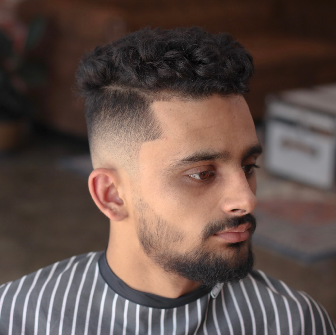 A textured curly fade with a sharp neckline, finished at Amunra Barbershop