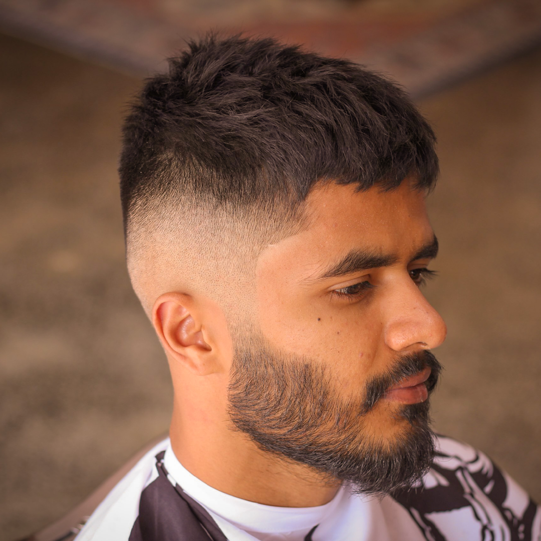A slicked side-part against a vintage steamer trunk at Amunra Barbershop