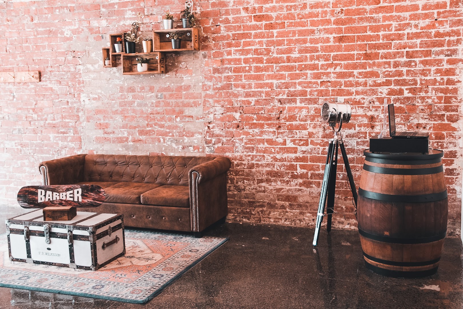 The leather chesterfield, whiskey barrel and vintage camera tripod inside Amunra Barbershop